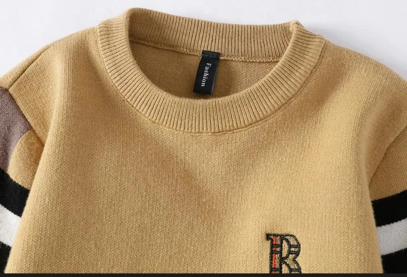 Close-up of a mustard yellow sweater with a brand label on a white background