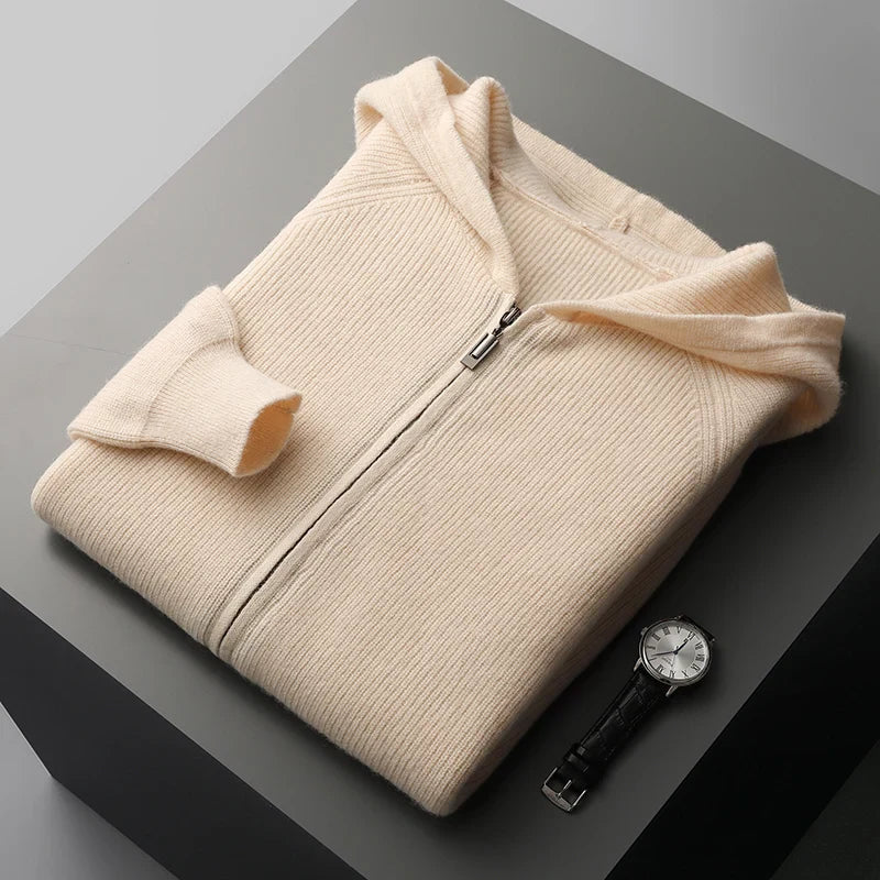 Folded beige sweater on a dark surface with a watch beside it