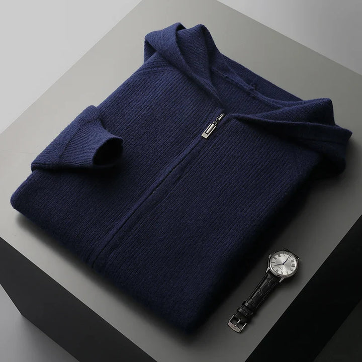 Folded navy blue sweater on a gray surface with a watch beside it