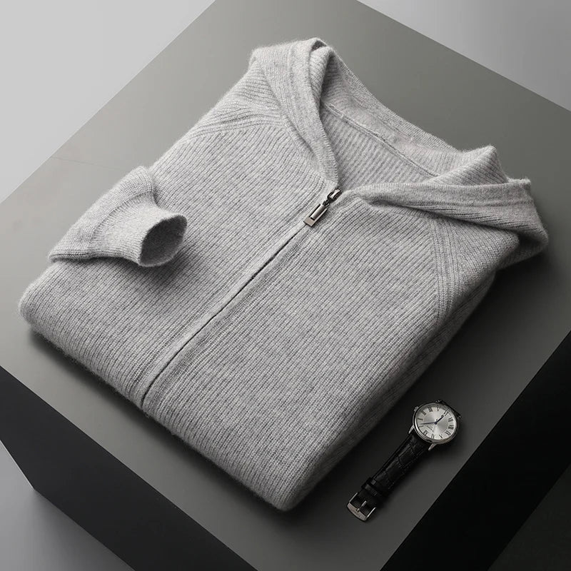 Folded gray hoodie on a dark surface with a watch beside it