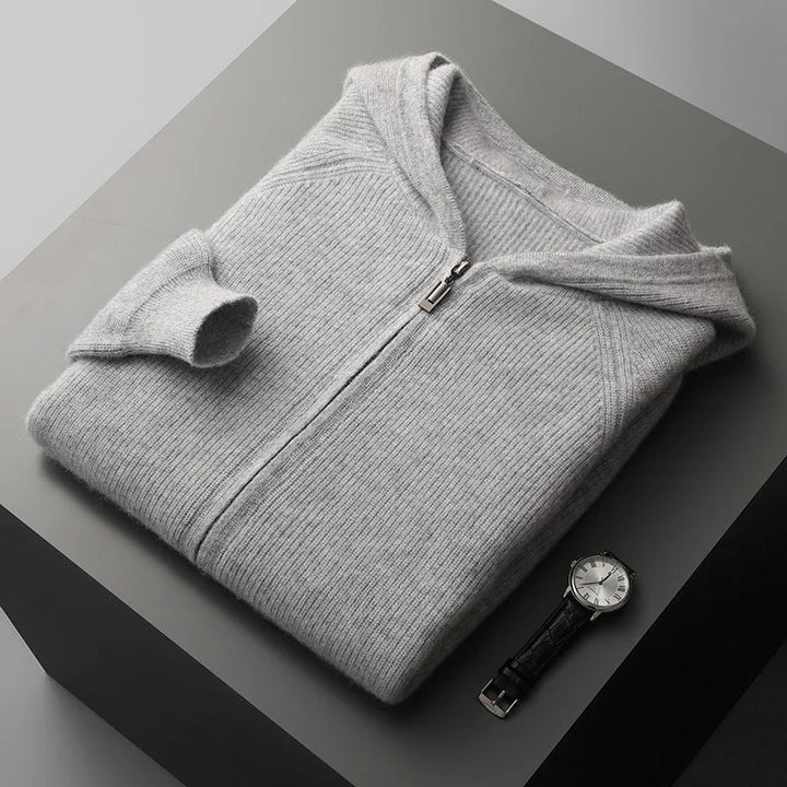 Folded gray hoodie on a dark surface with a watch beside it
