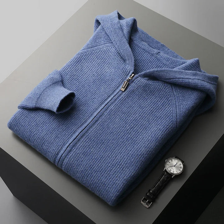 Folded blue sweater on a gray surface with a watch beside it