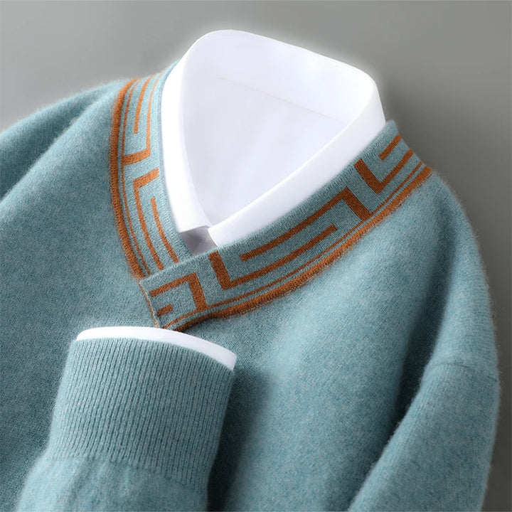 Teal sweater with brown pattern on neckline against a gray background