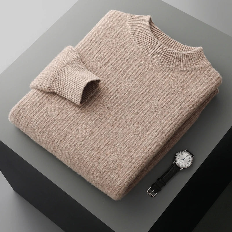 Folded beige sweater on a gray surface with a watch beside it