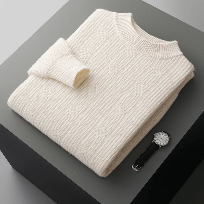Folded cream sweater on a dark surface with a watch beside it