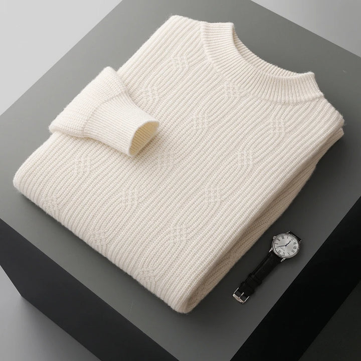 Folded cream sweater on a dark surface with a watch beside it