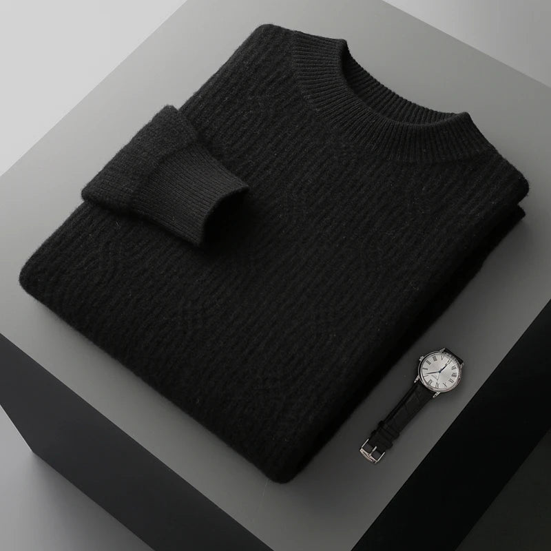 Folded black sweater on a gray surface with a watch and belt.