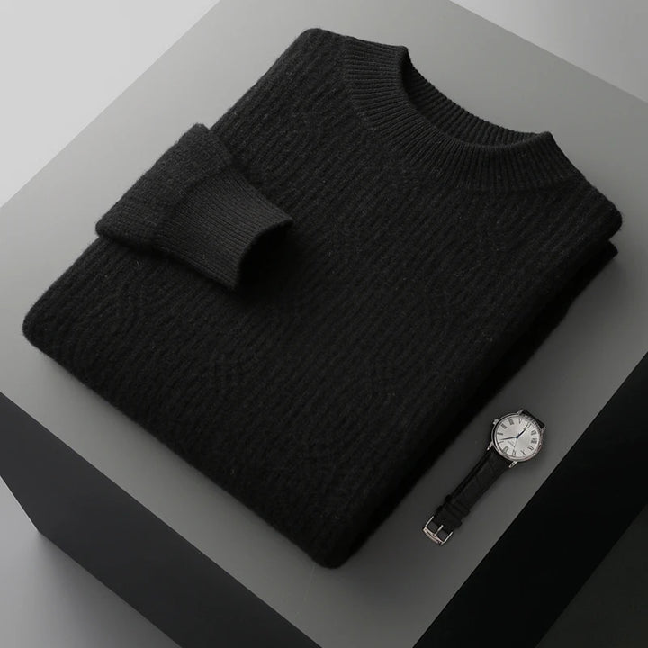 Folded black sweater on a gray surface with a watch and belt.