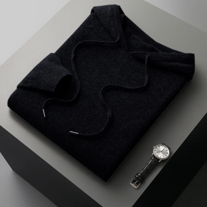 Folded dark gray sweater with a watch on a light gray surface