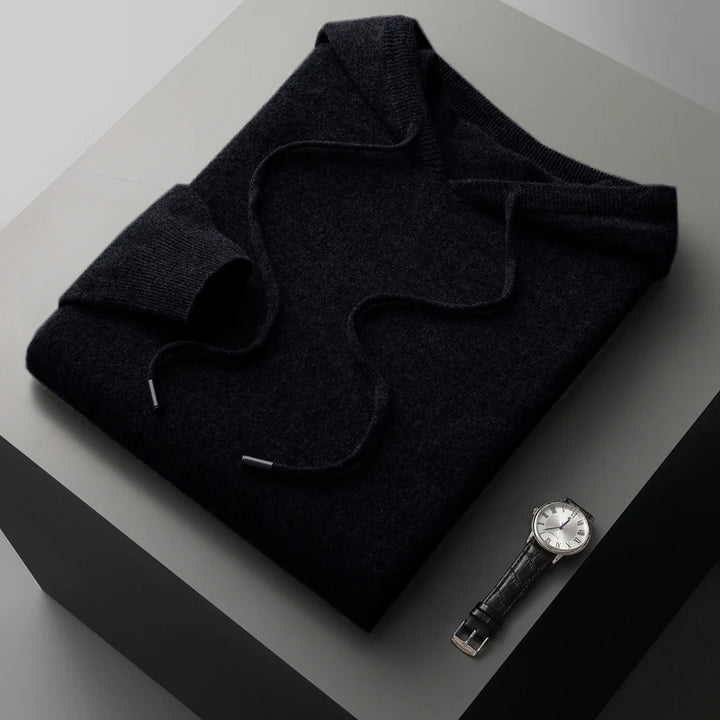 Folded dark gray sweater with a watch on a light gray surface