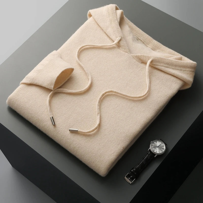 Beige hoodie folded on a dark surface with a watch beside it