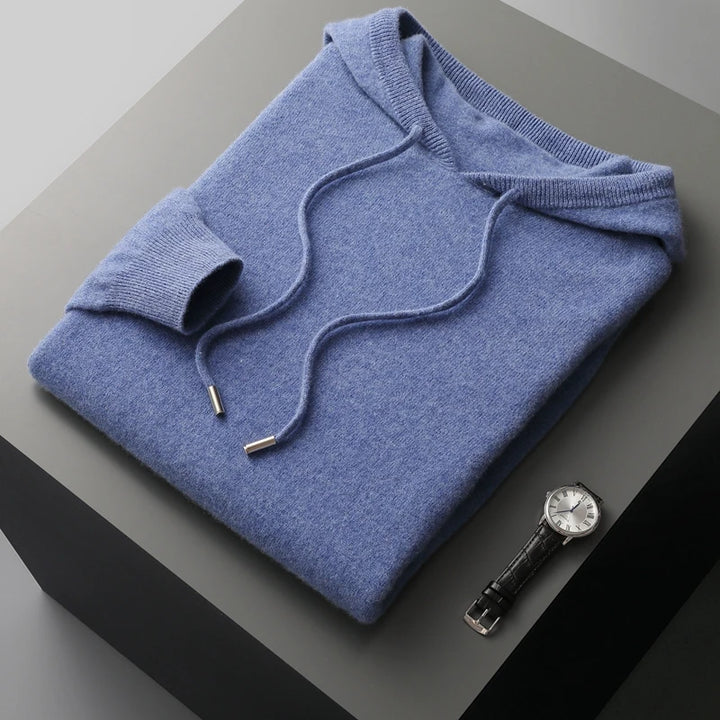 Folded blue hoodie on a gray surface with a watch beside it