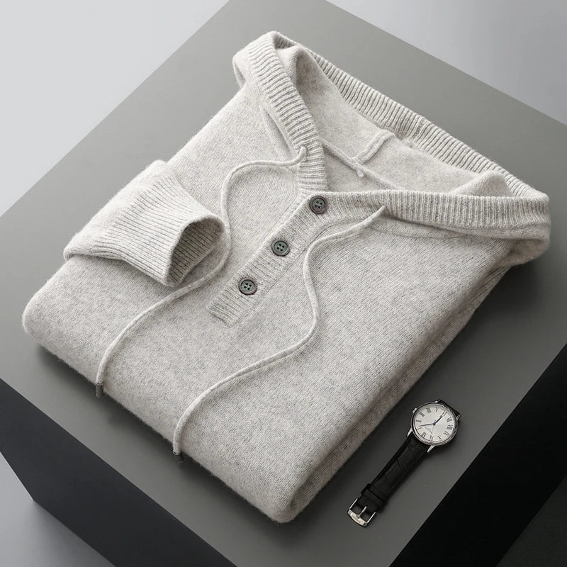 Folded gray sweater with a watch on a gray surface