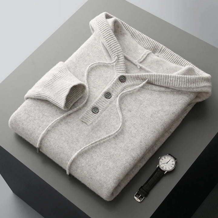 Folded gray sweater with a watch on a gray surface