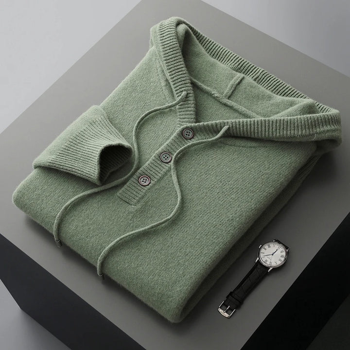 Folded green sweater with a watch on a gray surface