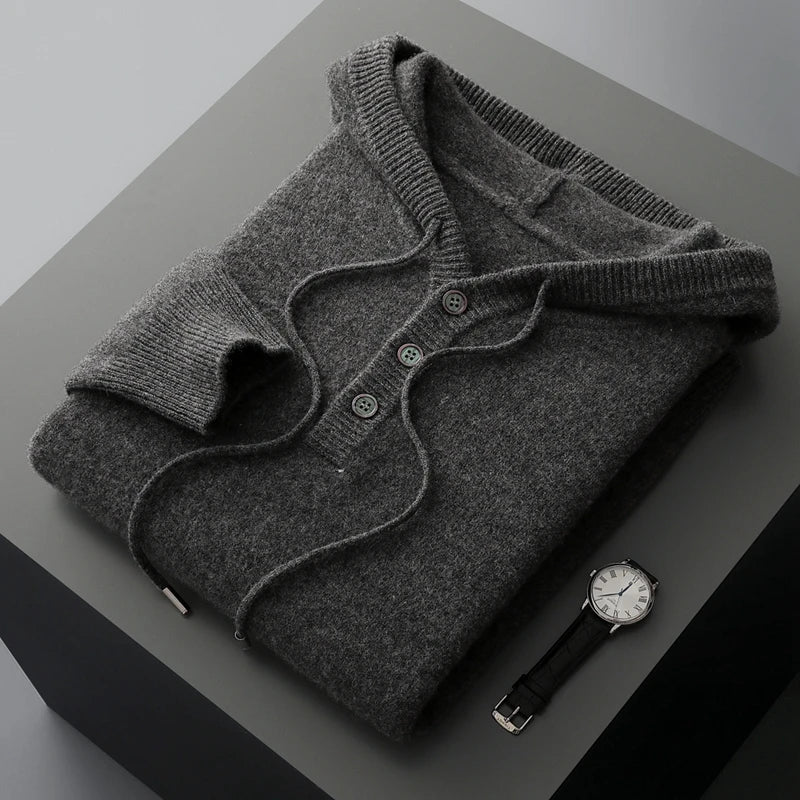 Folded gray sweater with a watch on a dark surface