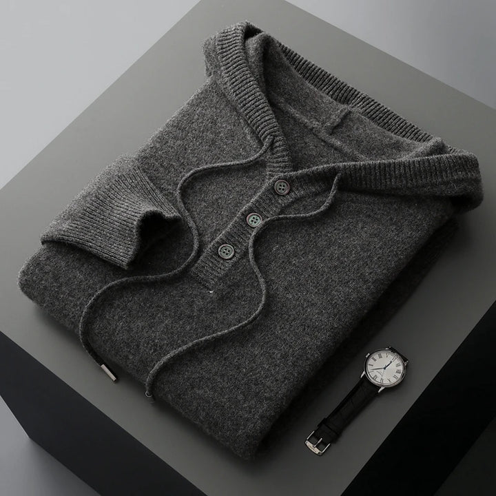 Folded gray sweater with a watch on a dark surface