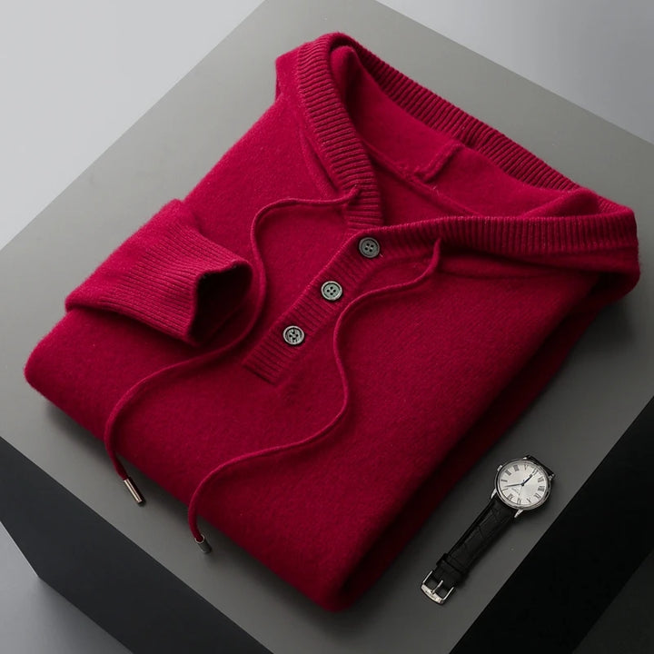 Folded red sweater on a gray surface with a watch beside it