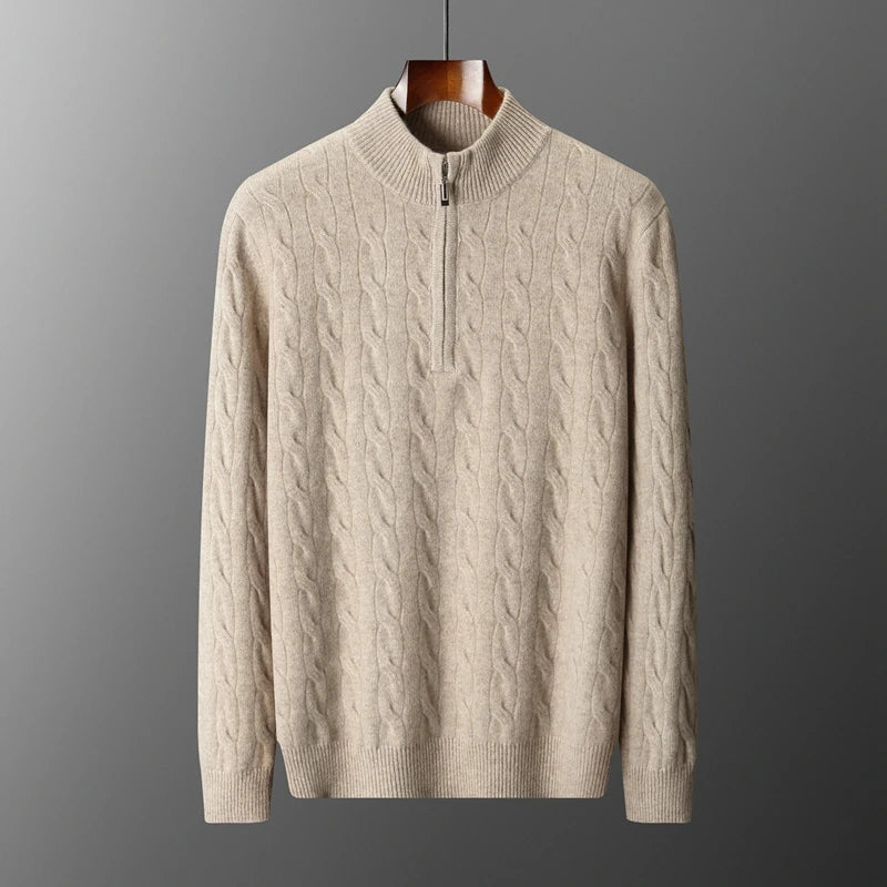 Beige cable knit sweater on a hanger against a gray background