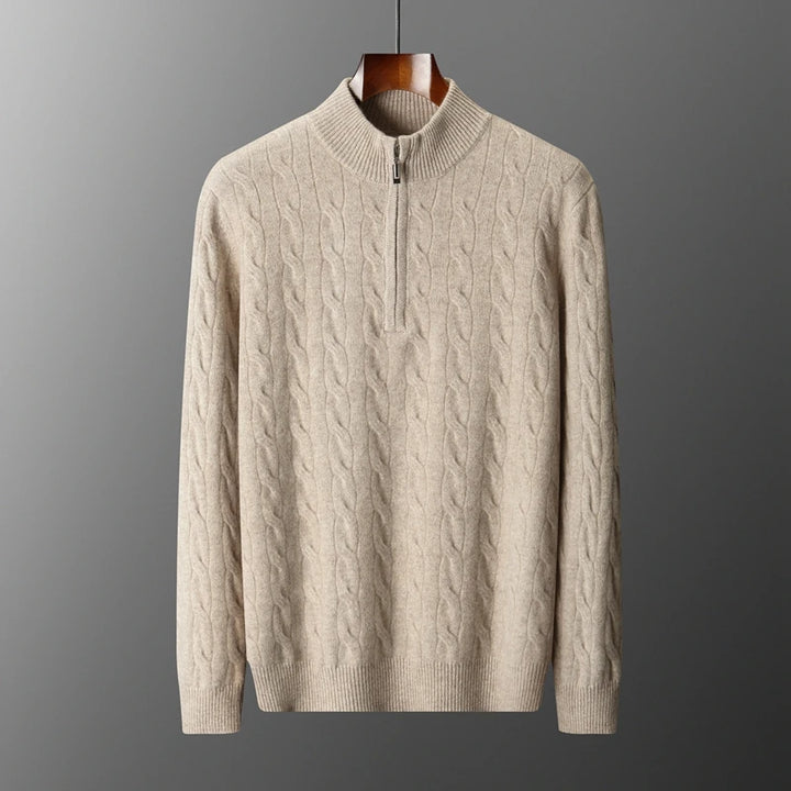Beige cable knit sweater on a hanger against a gray background