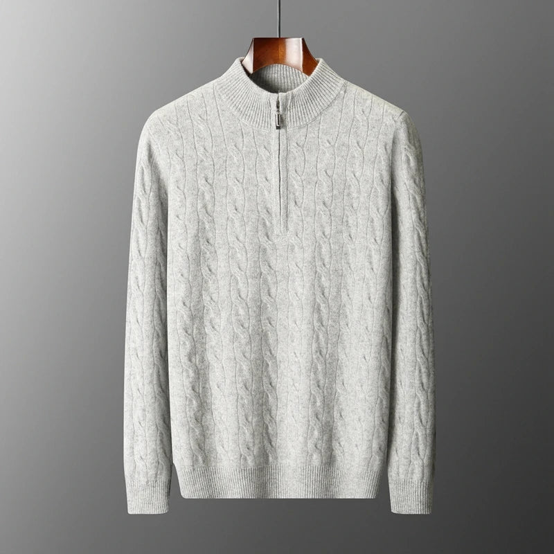 Gray cable knit sweater on a hanger against a gray background
