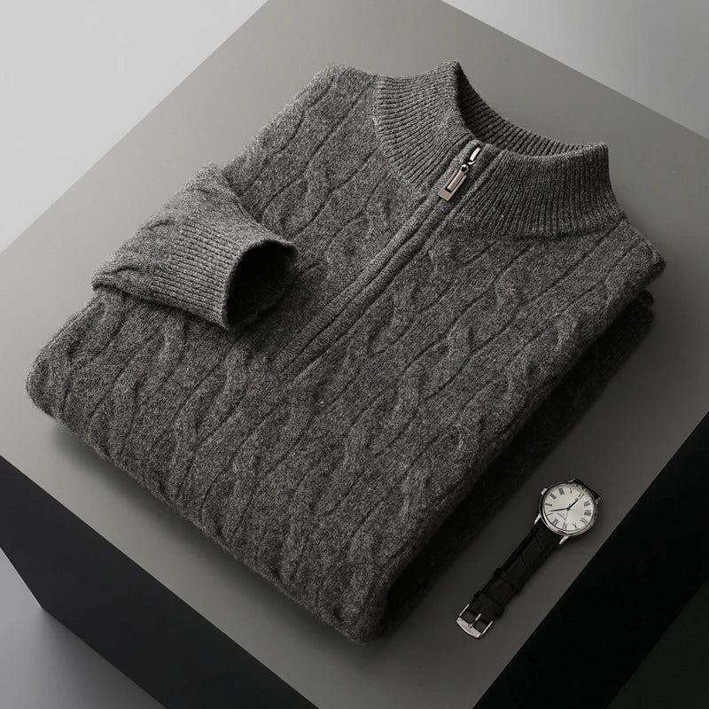 Folded gray cable knit sweater with a zipper on a dark surface, accompanied by a watch.