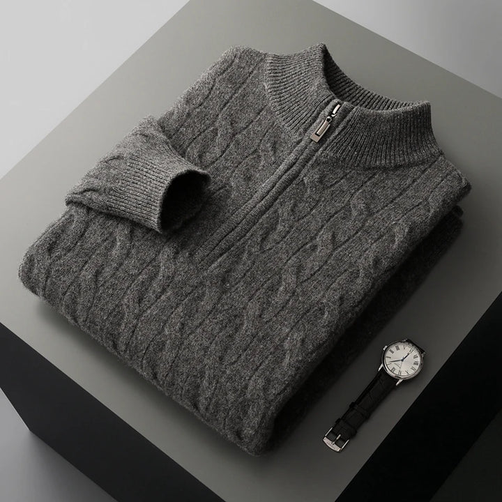 Folded gray cable knit sweater with a zipper on a dark surface, accompanied by a watch.