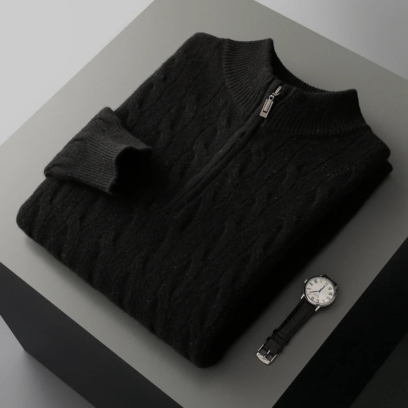Folded black sweater with a watch on a gray surface