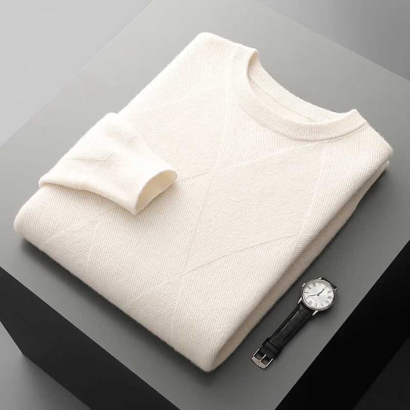 Folded cream sweater on a gray surface with a black wristwatch.