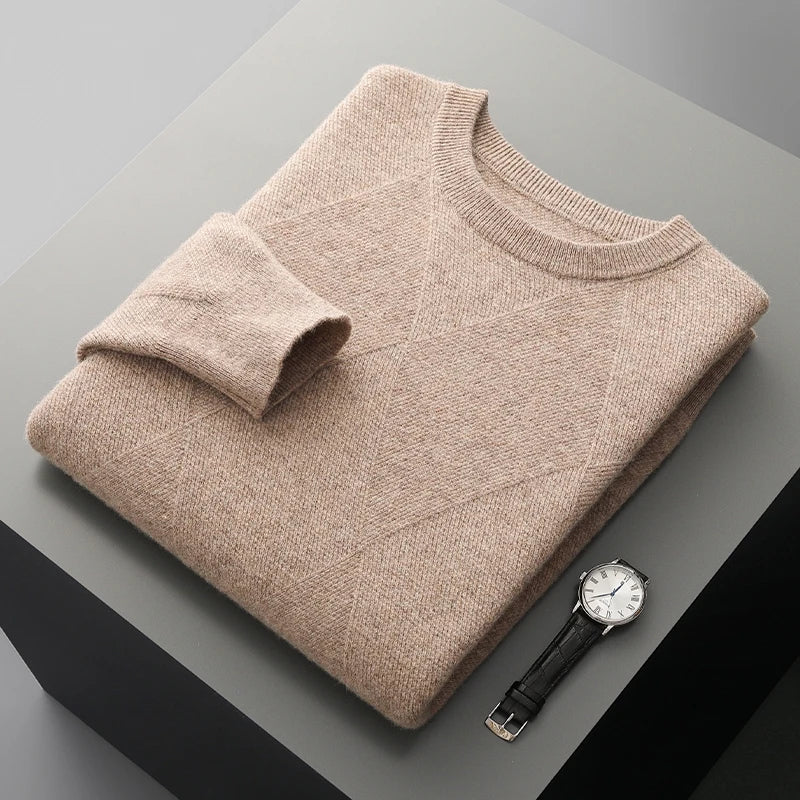 Folded beige sweater on a gray surface with a watch beside it