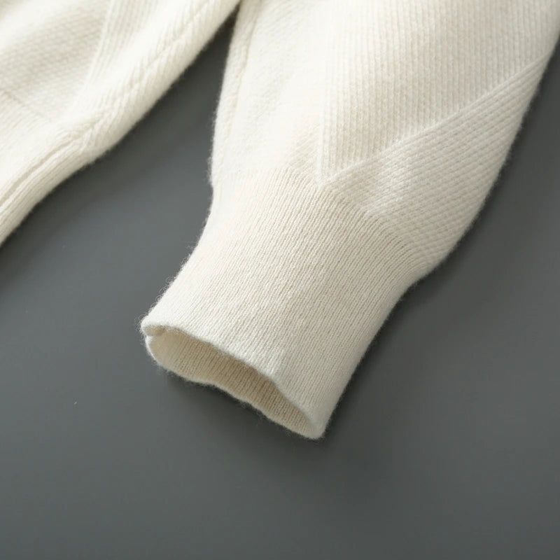 Close-up of a white knit sweater sleeve on a dark gray background