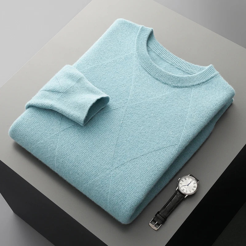 Folded light blue sweater on a gray surface with a watch next to it