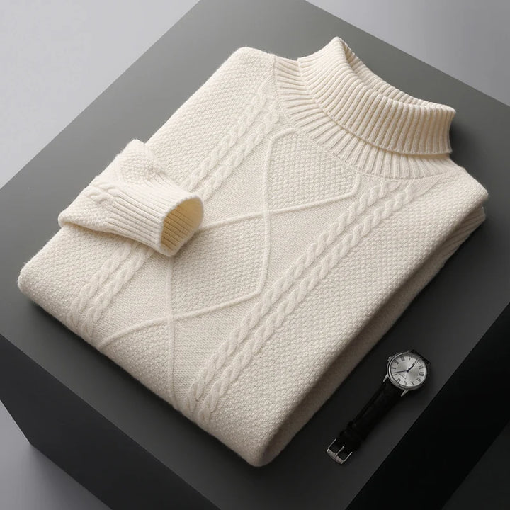 Folded cream sweater on a dark surface with a watch beside it