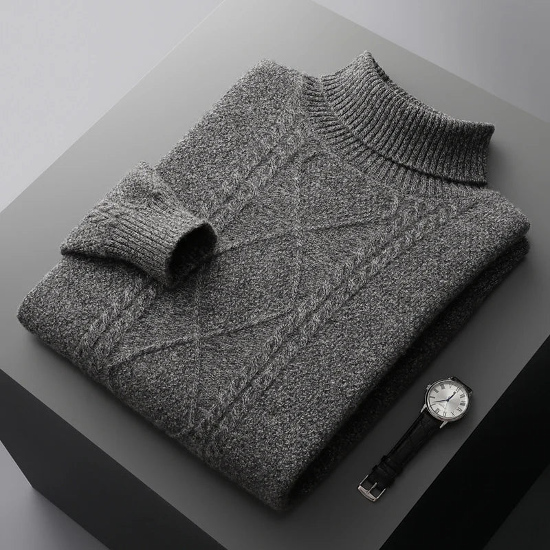 Folded gray sweater on a dark surface with a watch beside it