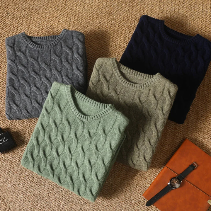 Four cable knit sweaters in gray, green, and black on a textured surface.