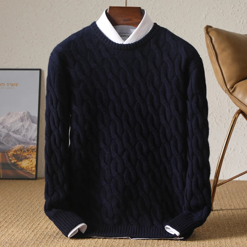 Navy blue cable knit sweater on a wooden hanger against a neutral background