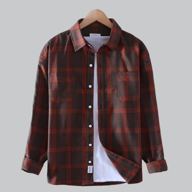 Brown and red plaid shirt on a hanger against a gray background
