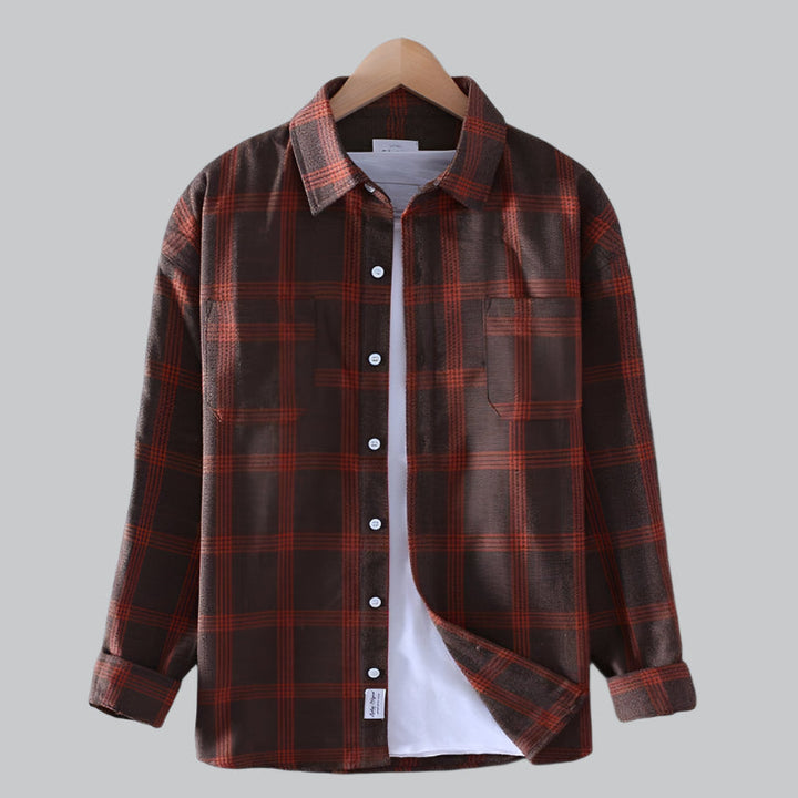 Brown and red plaid shirt on a hanger against a gray background
