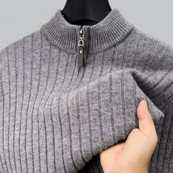 Gray ribbed sweater with a zipper held by a hand against a gray background