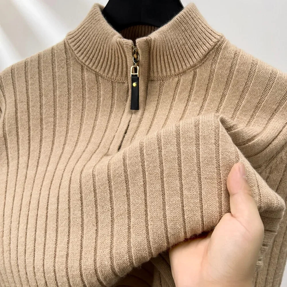 Beige ribbed sweater with a zipper held by a hand against a neutral background