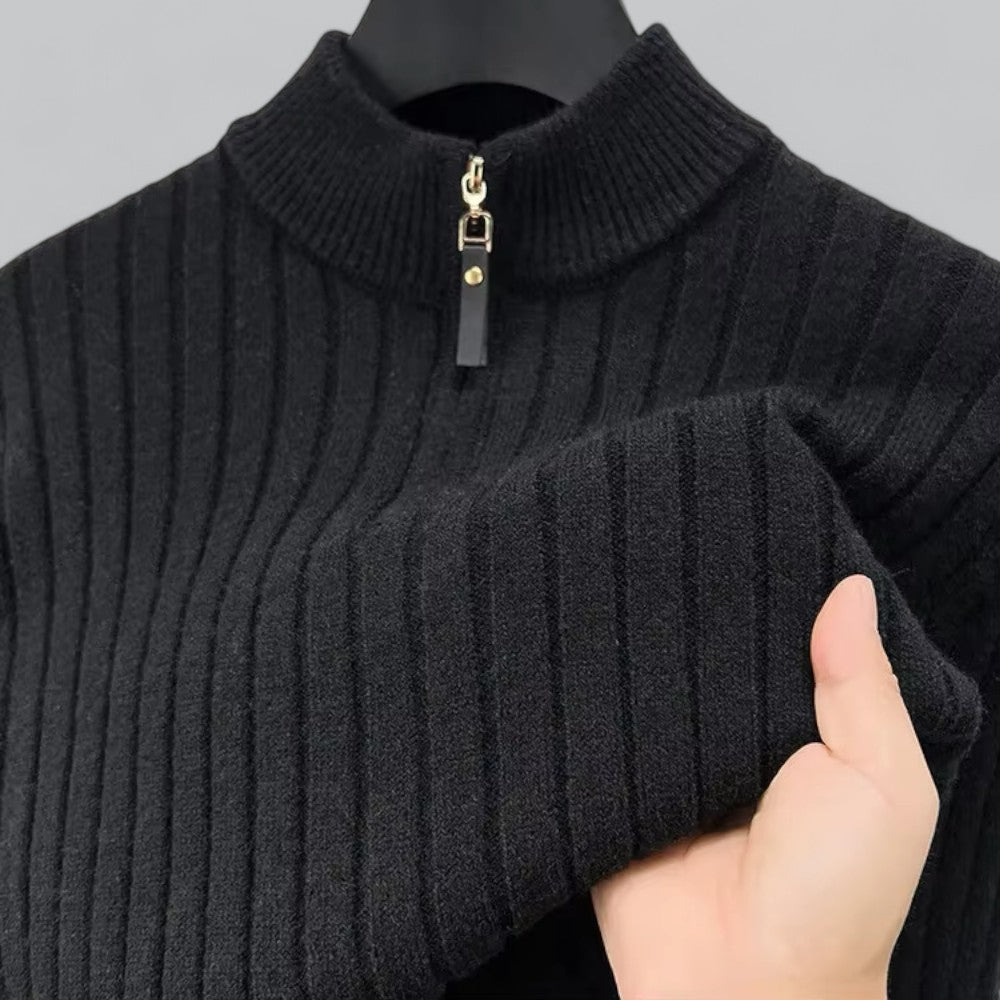 Dark gray ribbed sweater with a zipper held by a hand against a neutral background