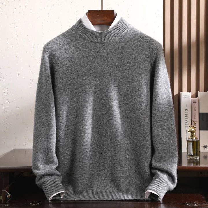 Gray sweater on a wooden hanger against a white wall.