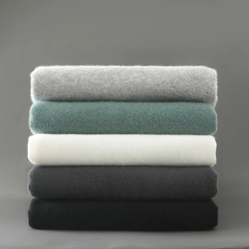 Stack of folded towels in gray, green, white, and black on a gray background