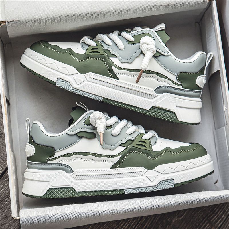 Green and white sneakers in a box on a wooden surface