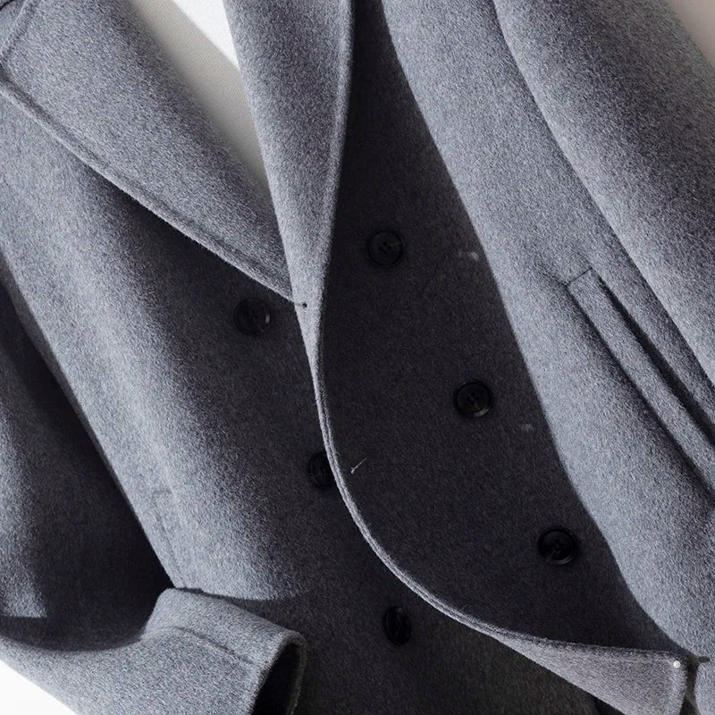 Close-up of a gray coat with black buttons on a white background
