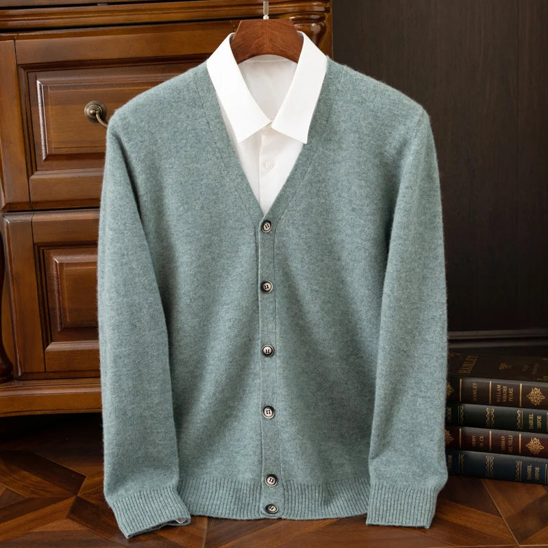 Green cardigan over a white shirt on a wooden hanger against a dark background.