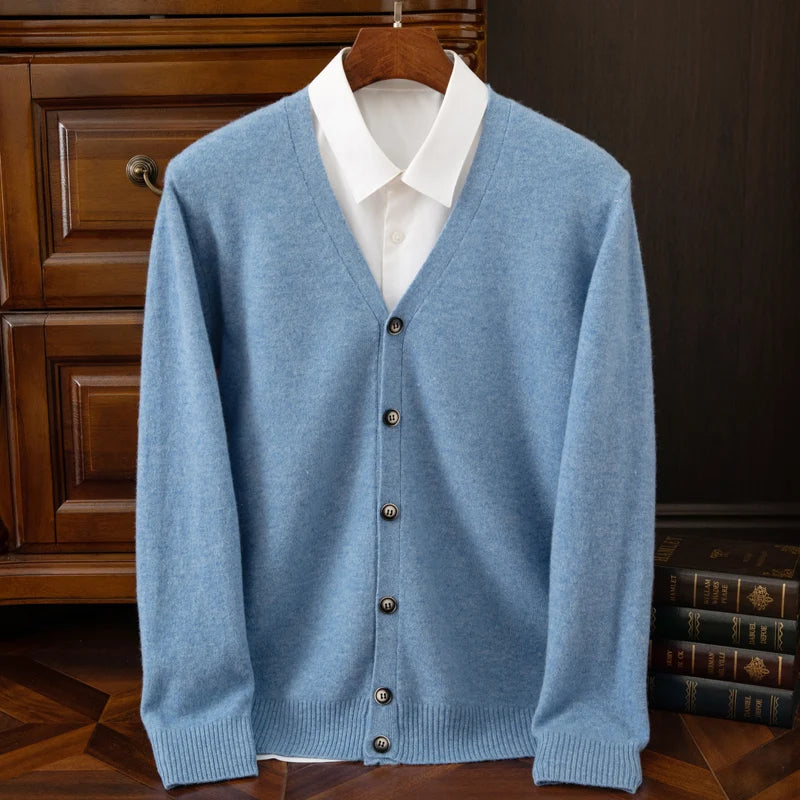 Blue cardigan over a white shirt on a wooden hanger against a dark background.
