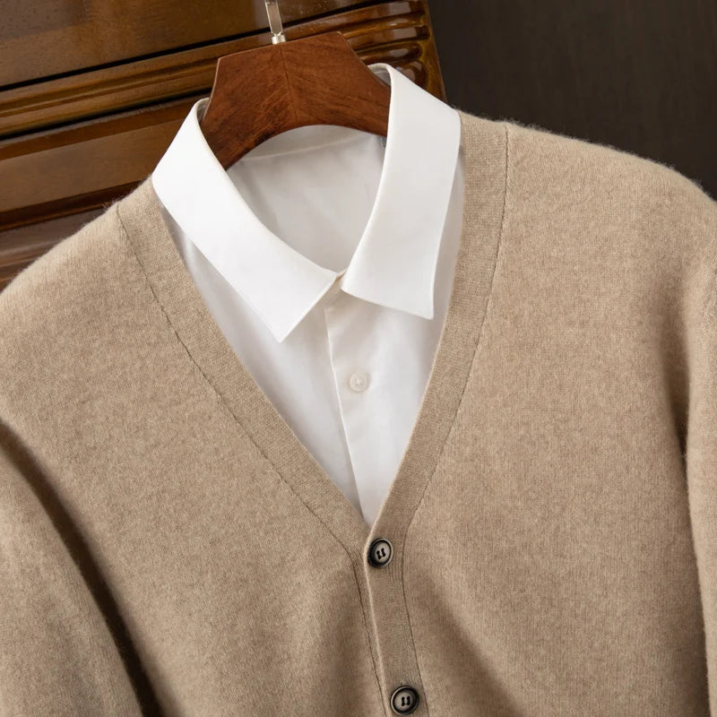 Beige cardigan over a white shirt on a wooden hanger against a dark background