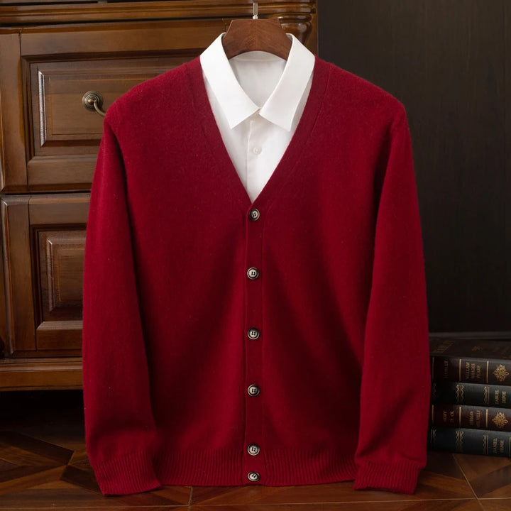 Red cardigan over a white shirt on a wooden hanger against a dark background.