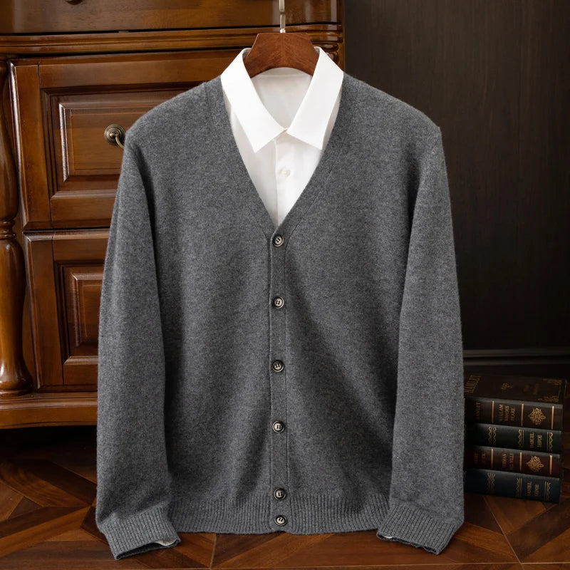 Gray cardigan over a white shirt on a wooden hanger against a dark background